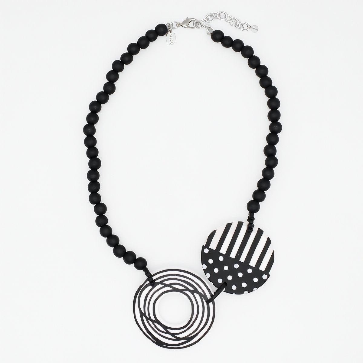 A black beaded statement necklace featuring two circular pendant elements: one with black and white stripes and one with black and white polka dots, displayed on a clean white background.