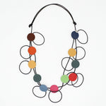 A modern multi-strand statement necklace featuring black elastic cords and multiple colorful circular discs in brown, orange, yellow, green, blue, pink, and red, displayed on a clean white background.
