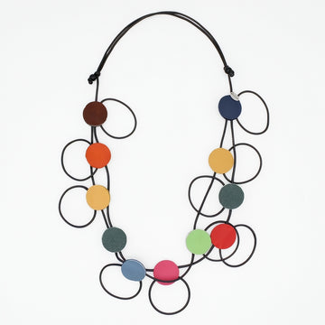 A modern multi-strand statement necklace featuring black elastic cords and multiple colorful circular discs in brown, orange, yellow, green, blue, pink, and red, displayed on a clean white background.
