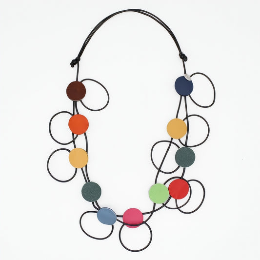 A modern multi-strand statement necklace featuring black elastic cords and multiple colorful circular discs in brown, orange, yellow, green, blue, pink, and red, displayed on a clean white background.