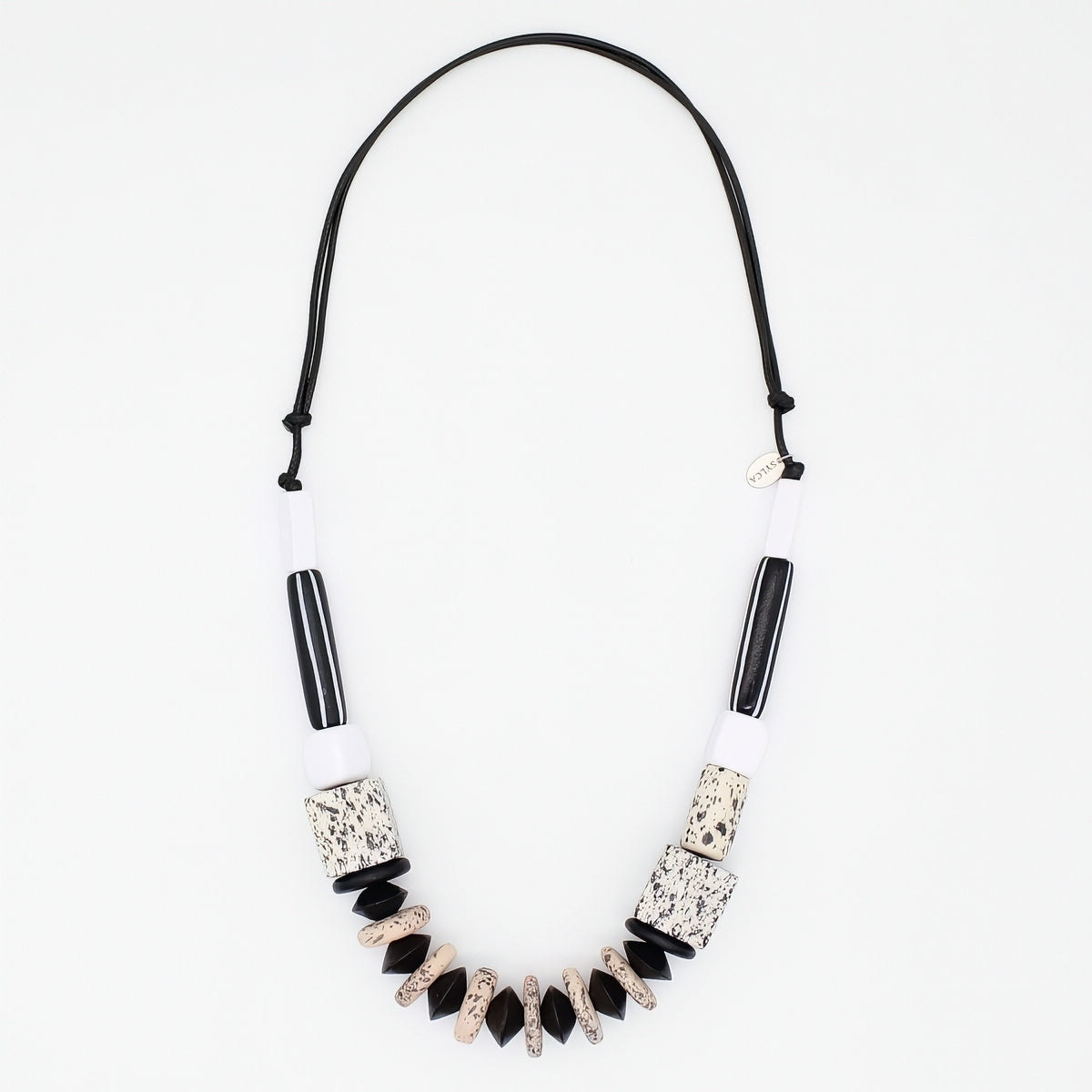 A statement necklace featuring a black cord, white cylindrical beads, black striped beads, and textured black and beige geometric beads, displayed on a clean white background.