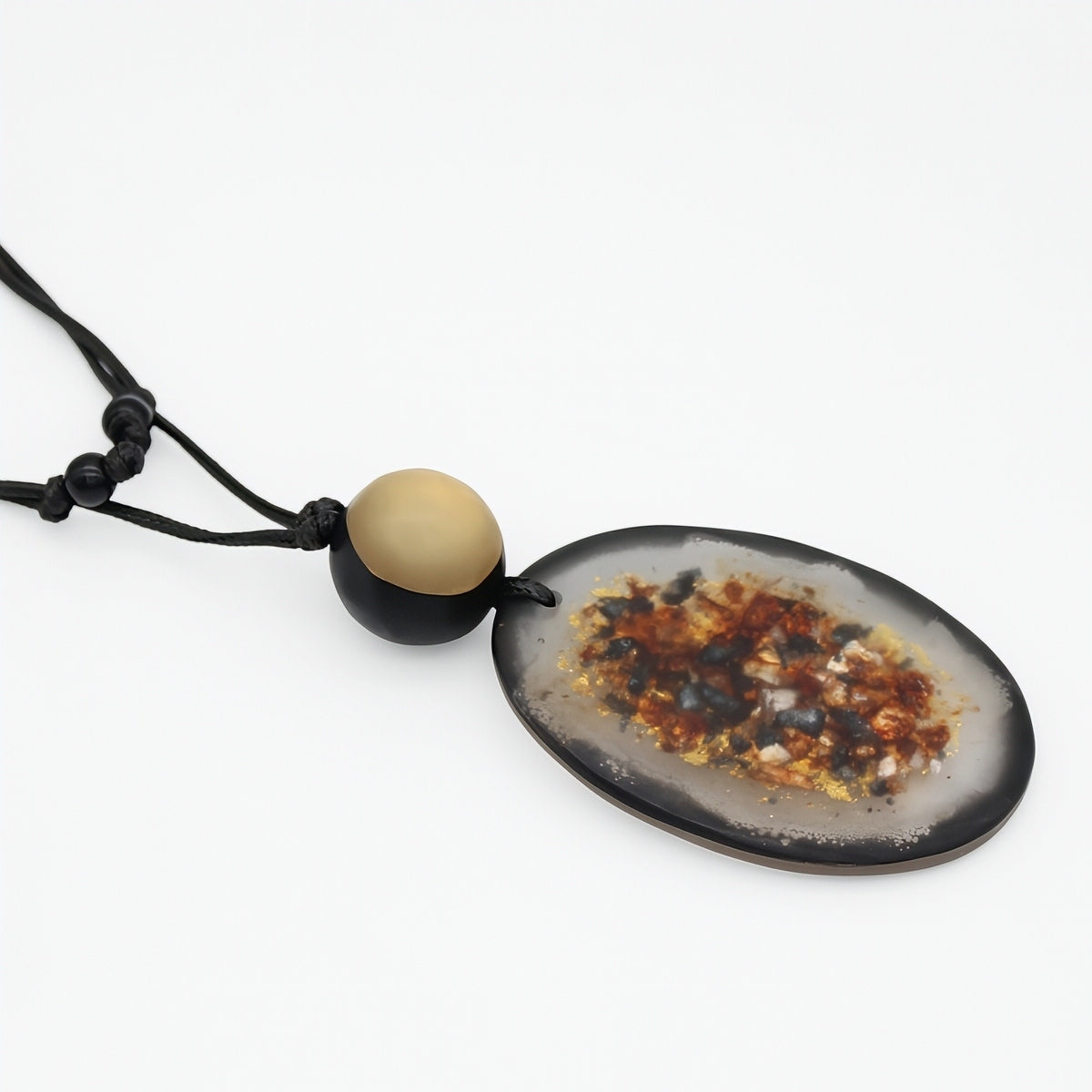 A natural agate geode pendant necklace on a black cord, featuring a polished oval agate slice with a dark rim and colorful crystalline core, accented by a round beige bead on the cord.