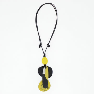 A modern abstract pendant necklace featuring a black cord and a multi-layered pendant with yellow, black, and white organic shapes, shown against a plain white background.