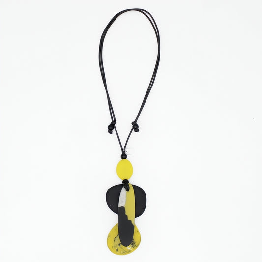 A modern abstract pendant necklace featuring a black cord and a multi-layered pendant with yellow, black, and white organic shapes, shown against a plain white background.