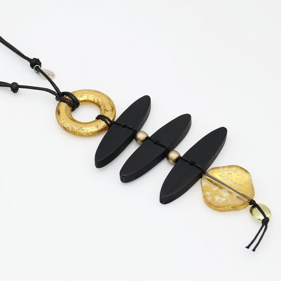 Close up of sculptural black wood necklace and gold resin accents