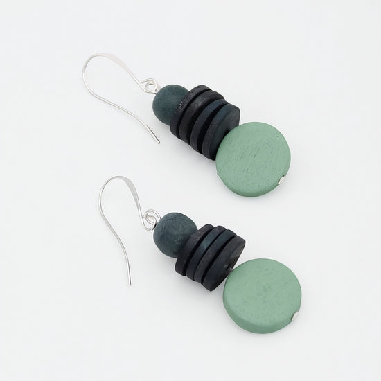 Pair of earrings with black and green circular beads on a white background