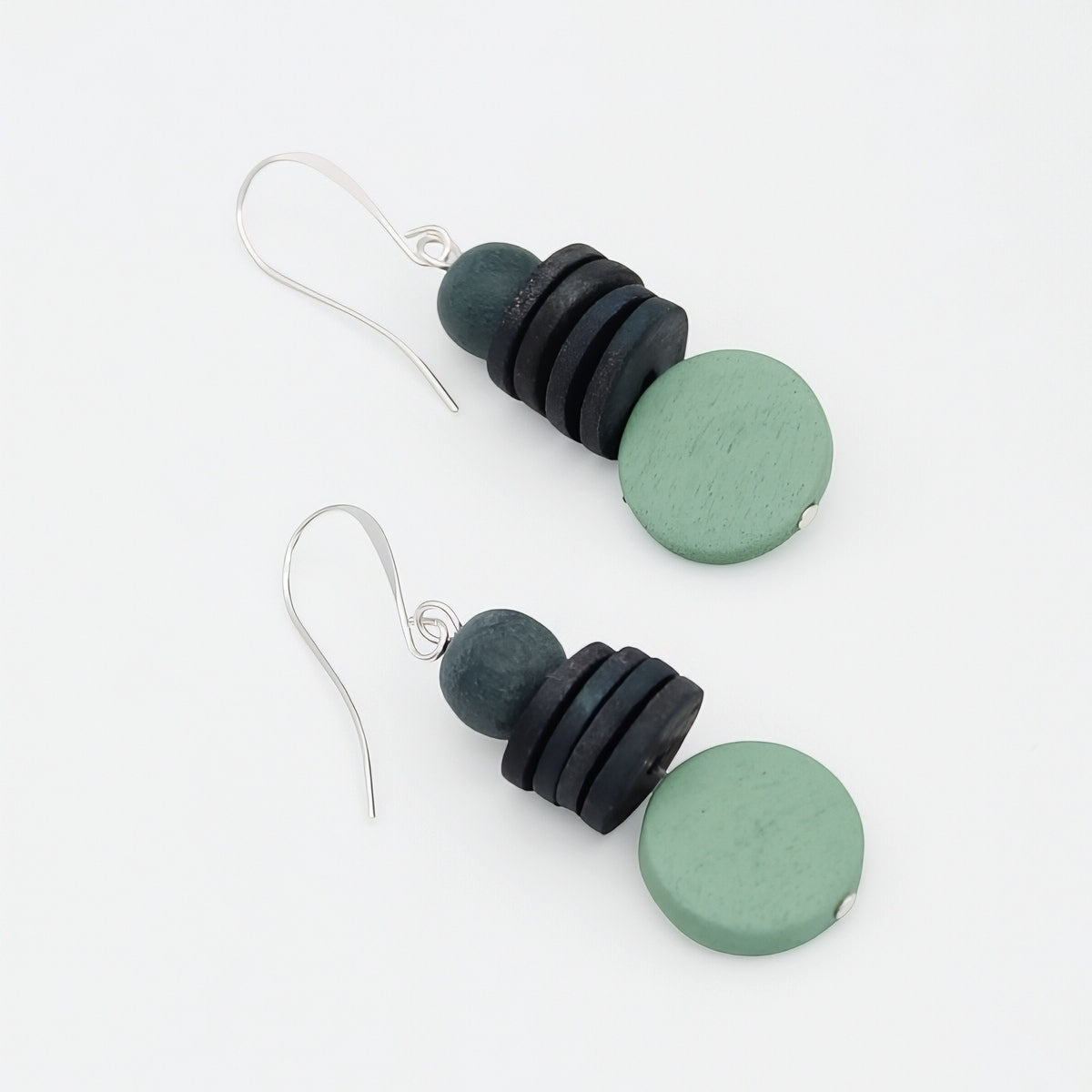 Pair of earrings with black and green circular beads on a white background