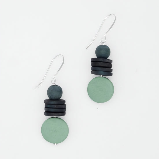 Pair of earrings with green and black circular beads on a white background