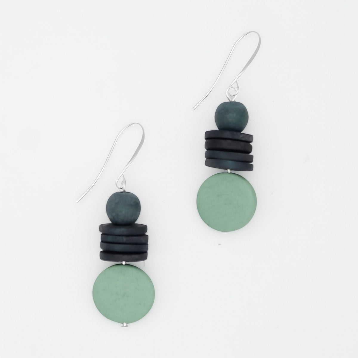 Pair of earrings with green and black circular beads on a white background