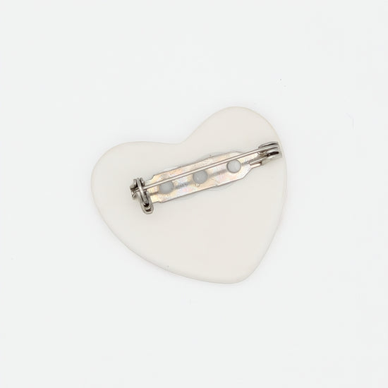Heart-shaped brooch with a silver bar on a white background