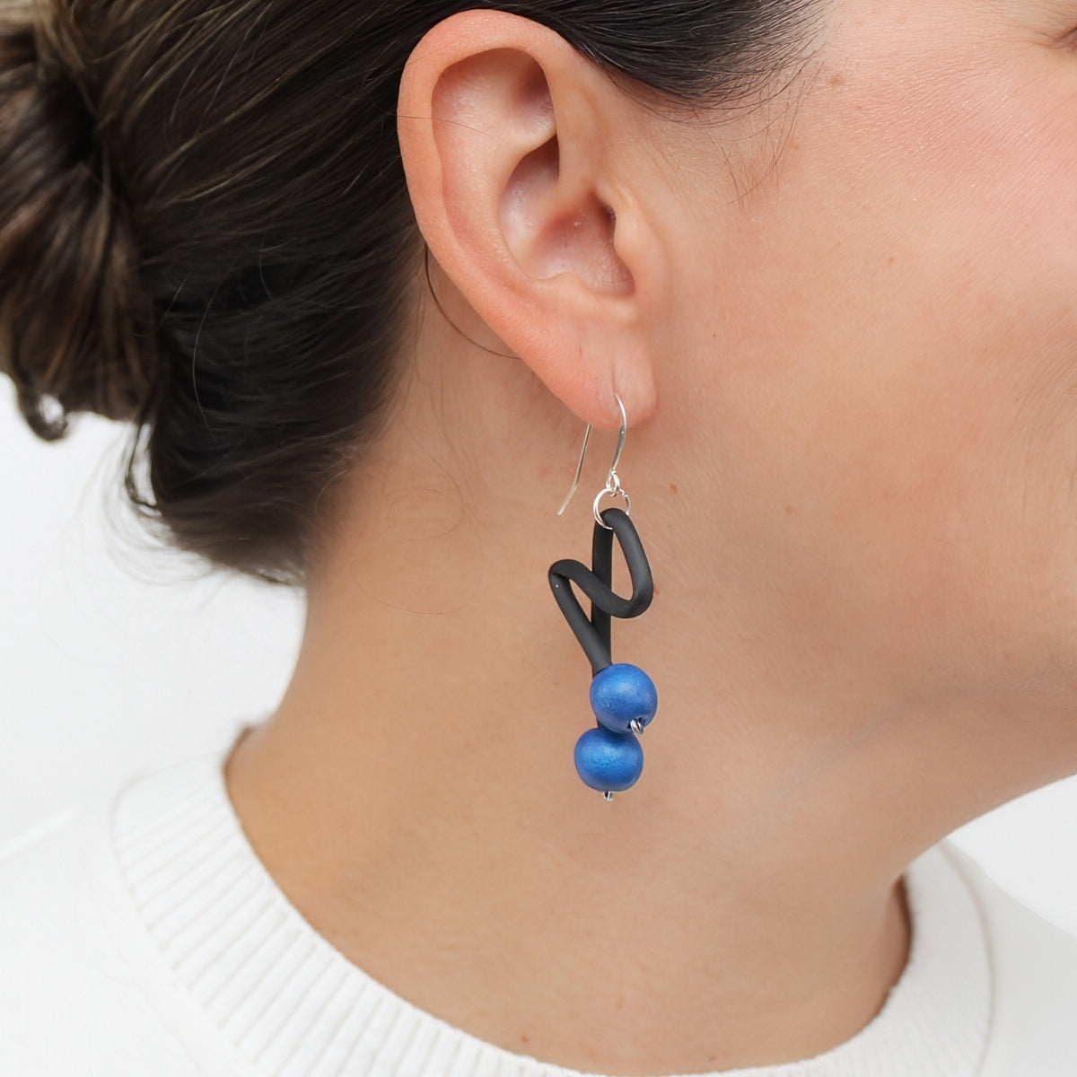 Blue and black sculptural earrings shown on model