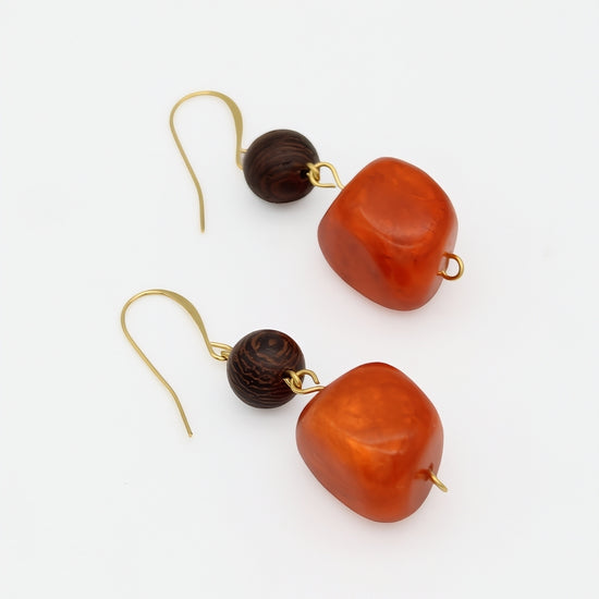 Orange resin and wood statement earrings angled product view