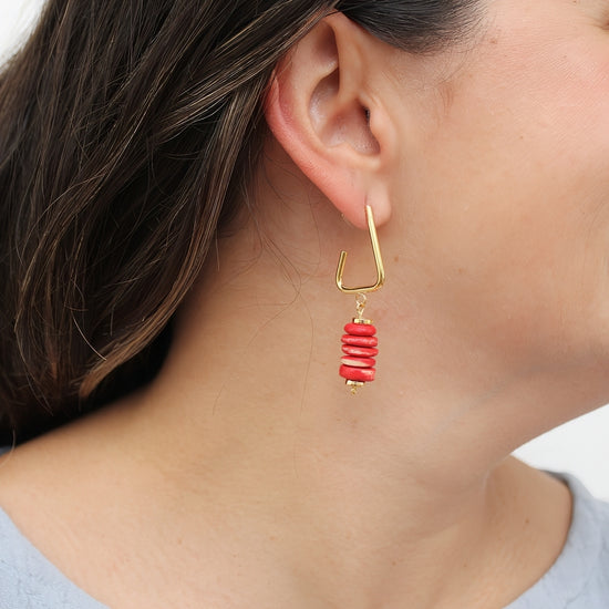 Red statement earrings shown on model