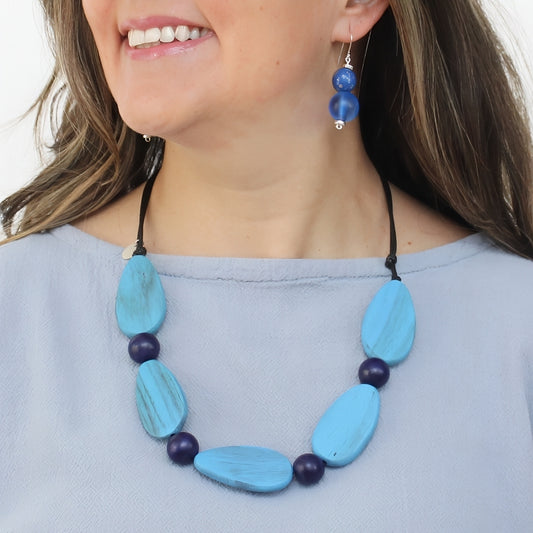 Woman wearing a blue beaded necklace and earrings on a white background