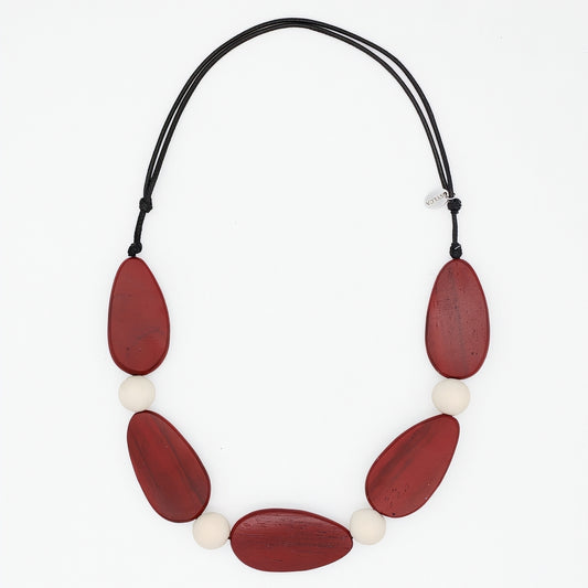Necklace with red and white beads on a black cord against a white background