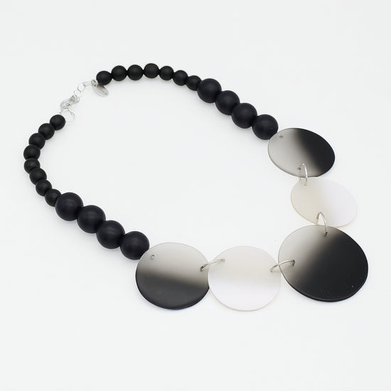 Necklace with black beads and gradient disc pendants on a white background