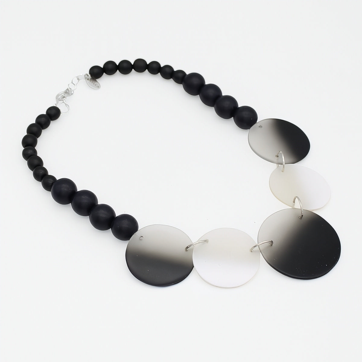 Necklace with black beads and gradient disc pendants on a white background
