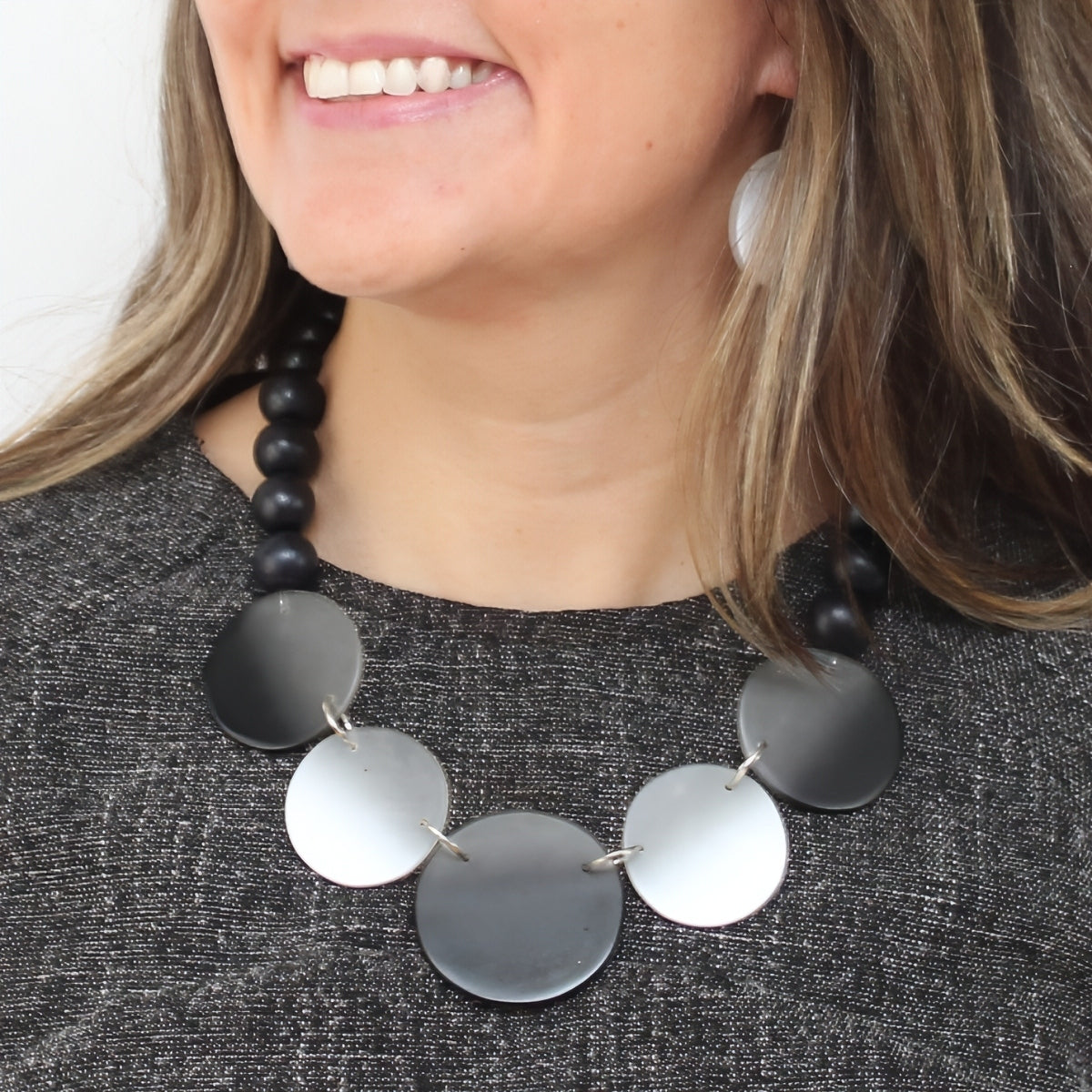 Necklace with black and silver circular pendants worn by a person