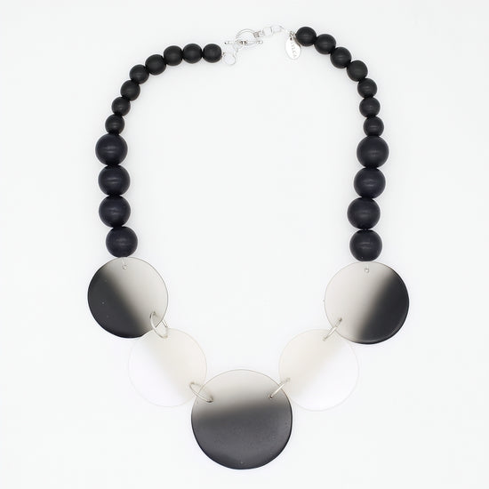 Necklace with black beads and round metallic discs on a white background