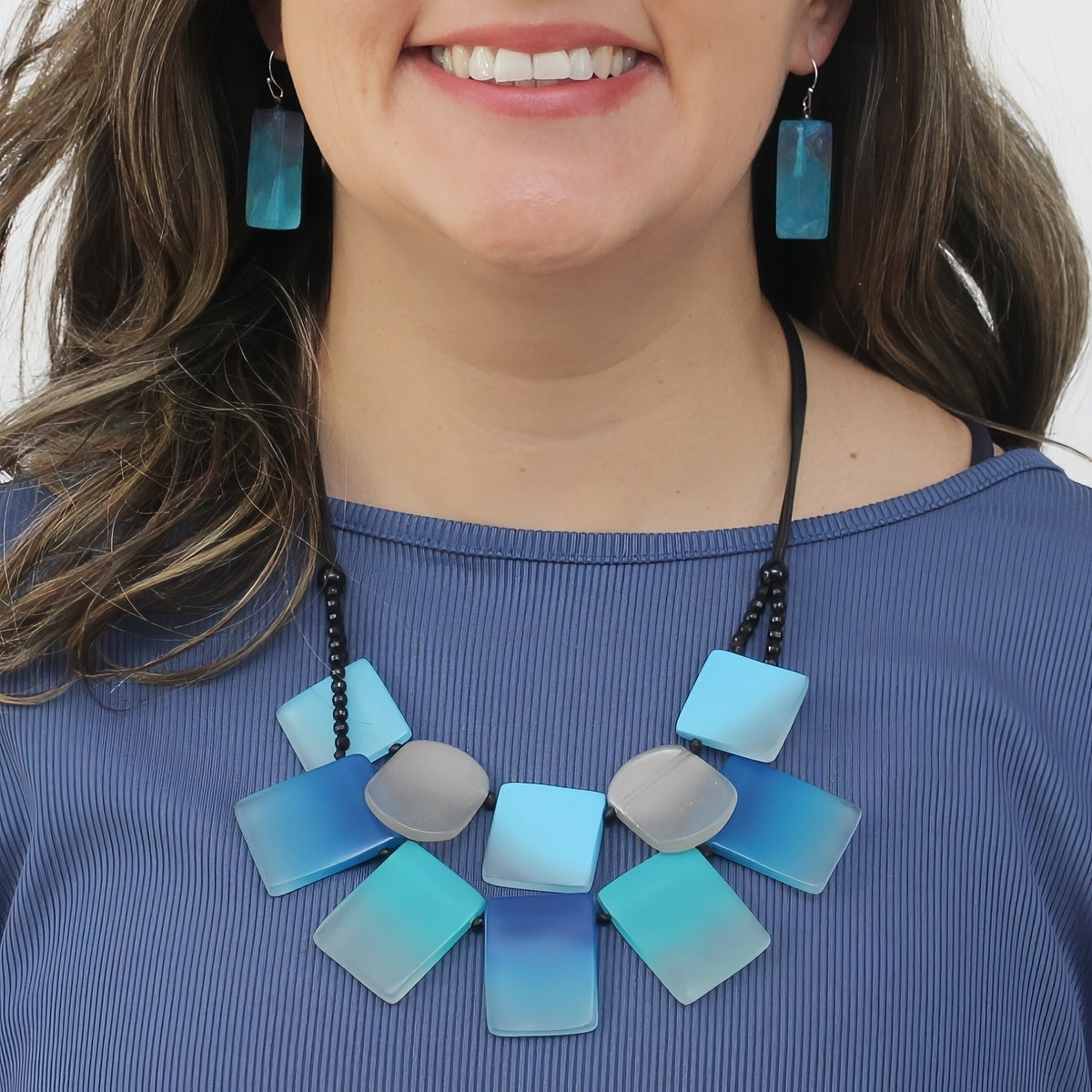 Woman wearing a blue and silver necklace with matching earrings on a white background