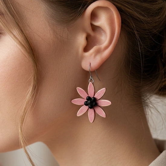 Close-up of a woman wearing pink flower earrings with a blurred floral background