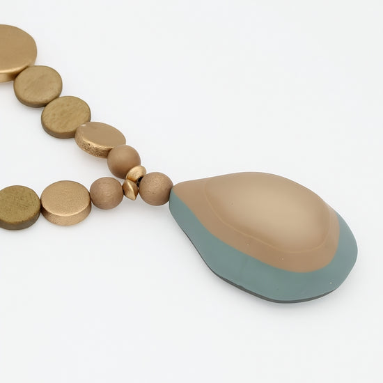 Close up of taupe layered resin pendant and gold wood beads