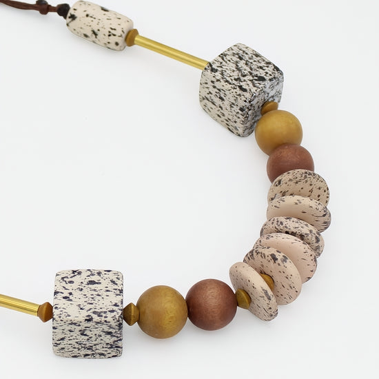 Close up of natural wood necklace with speckled cream beads, wood beads and gold accents