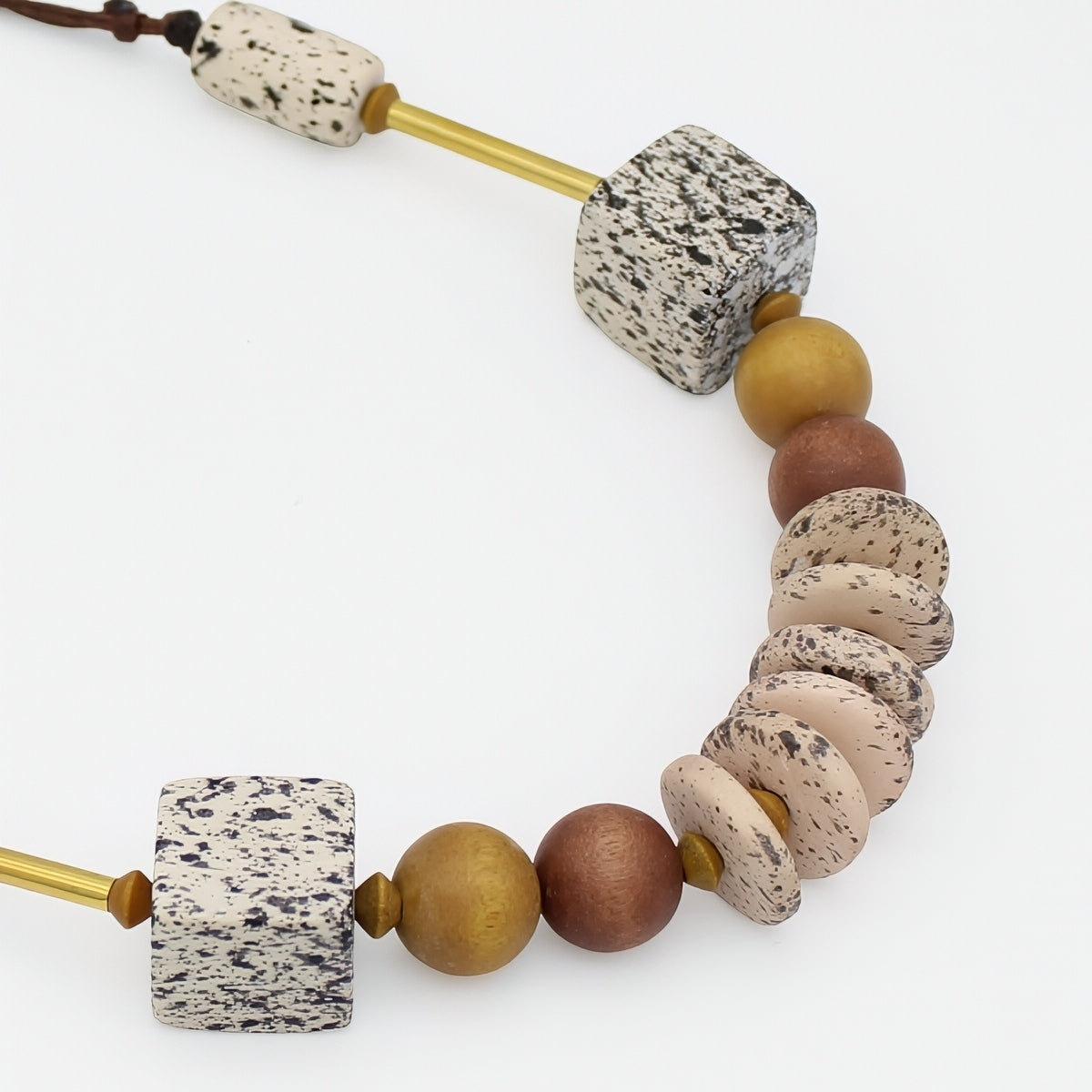 Close up of natural wood necklace with speckled cream beads, wood beads and gold accents