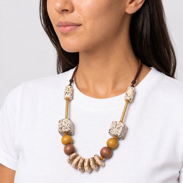 Natural wood statement necklace with speckled cream beads and gold accents worn on model