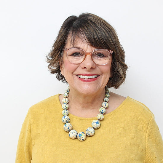 woman in yellow top wearing wood colorful necklace